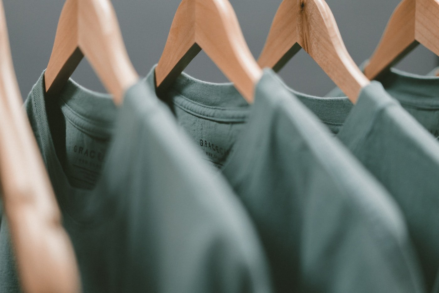 Sage t-shirts on wooden hangers